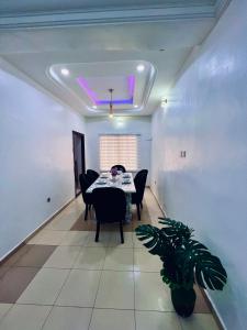 un comedor con mesa, sillas y una planta en The Blcksite: A 3 bedroom apartment in Wuse, en Abuja