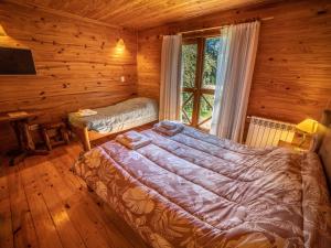 a bedroom with a bed in a log cabin at Hosteria Pichi Rincon in Villa La Angostura