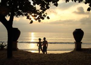 una pareja de pie en la playa al atardecer en InterContinental Bali Resort, an IHG Hotel en Jimbaran