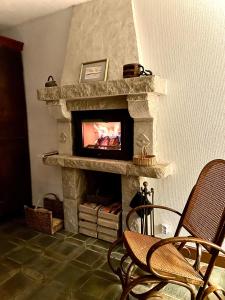 a living room with a stone fireplace with a tv at La Capitainerie, la plage à 5 minutes à pied ! in Fréhel