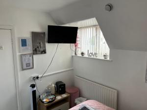 a bedroom with a bed and a television on the wall at The Southwold Guest House in Skegness