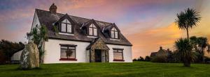 a white house with a black roof on a green field at Gunpoint Lodge, Schull, West Cork with Private Pier in Seafort