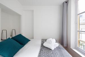 ein weißes Schlafzimmer mit einem Bett mit Handtüchern darauf in der Unterkunft LE CORSAIRE - Petit cocon dans lIntra-Muros in Saint-Malo