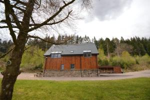 ein großes Holzgebäude mit einer Bank auf einem Feld in der Unterkunft Tall Pines Apartment in Spean Bridge