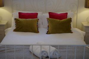 a bed with red and white pillows and a white bedskirts at Stunning pied-a-terre moments from the water. in Netley