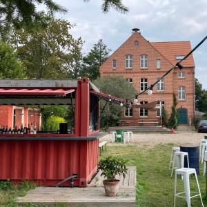 a red building with tables and chairs in front of a building at Hug&Dim im Gasthaus am Finowkanal in Wandlitz