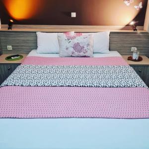 a bedroom with a large bed with pink sheets and pillows at Hotel Bulevar in Bitola
