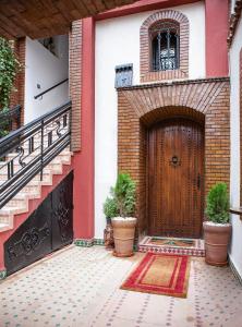 a house with a wooden door with two potted plants at RIAD DOUIRTNA in Marrakech
