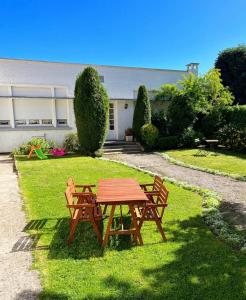 een picknicktafel en twee banken in een tuin bij Hotel Joly in Armentières