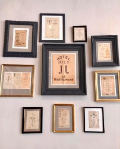 a wall with framed diplomas and certificates at Hotel Joly in Armentières