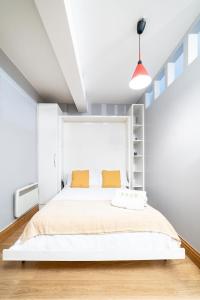 een slaapkamer met een groot wit bed met oranje kussens bij (St' Paul Cathedral) London Studio Apartment in Londen