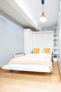 a white bedroom with a large white bed with orange pillows at (St' Paul Cathedral) London Studio Apartment in London