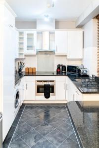 a kitchen with white cabinets and a dishwasher at (St' Paul Cathedral) London Studio Apartment in London