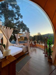 um quarto com uma cama e uma grande janela em Zion Bubble Glamping em Urubici