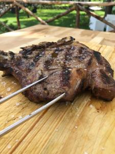a piece of meat on a wooden cutting board with tongs at DONNA ROSITA in San Felice a Cancello