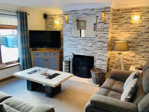a living room with a fireplace and a tv at Aonachan Cottage in Spean Bridge