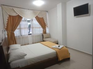 a small bedroom with a bed and a window at Hotel Quezada Hermanos in Santo Domingo de los Colorados