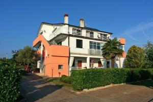 une grande maison blanche et orange avec un palmier dans l'établissement Apartments and rooms with a swimming pool Babici, Umag - 3046, à Umag