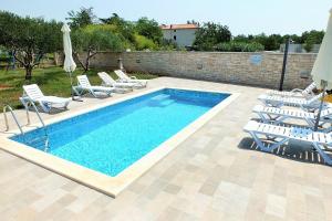 a swimming pool with lounge chairs and an umbrella at Apartments and rooms with a swimming pool Babici, Umag - 3046 in Umag