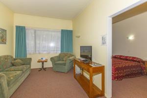 a living room with a couch and a chair at Fernhill Motor Lodge in Lower Hutt