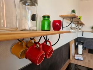 un groupe de tasses à café suspendues sur une étagère dans l'établissement Appartement Mâcon Centre T4 - 100m2, à Mâcon