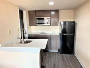 uma cozinha com um frigorífico preto e um lavatório em James River Inn & Suites em Newport News