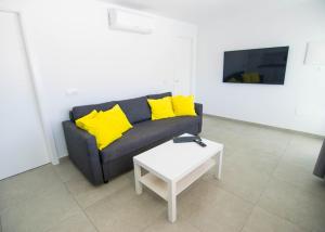 sala de estar con sofá, almohadas amarillas y mesa en Apartamentos Alcalá - Tenerife, en Alcalá