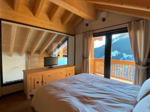 sypialnia z łóżkiem i dużym oknem w obiekcie Chalet Ronchi - Foppolo Ski w mieście Foppolo