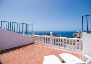 a balcony with white chairs and a view of the ocean at Apartamentos Alcalá - Tenerife in Alcalá