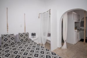 a white room with a bed and a kitchen at Eris Studios in Adamas