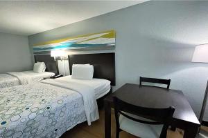 Cette chambre d'hôtel comprend deux lits, une table et une chaise. dans l'établissement HomeTowne Studios By Red Roof Augusta, à Augusta
