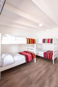 two white bunk beds in a room with wooden floors at Hostal Copart in San Pedro de Atacama
