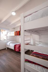 a bedroom with white bunk beds in a room at Hostal Copart in San Pedro de Atacama