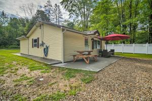a small house with a picnic table and umbrella at Jamestown Retreat with Hot Tub - Walk to Lake! in Hartstown