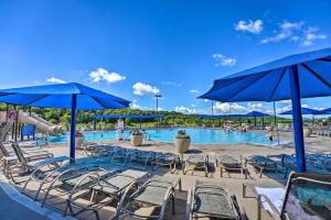 a pool with chairs and blue umbrellas and people in the water at Family-Friendly Galena Townhome with Community Pools in Galena