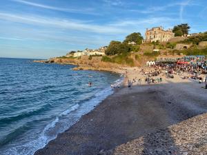 un grupo de personas en una playa cerca del agua en Harbour View Ground Floor Flat with Private Parking, only 5 Mins walk to harbour, en Brixham