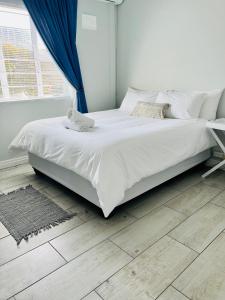 a white bed in a bedroom with a blue curtain at Bella Lux Villa in Durban