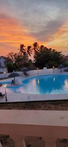 ein großer Pool mit Sonnenschirmen bei Sonnenuntergang in der Unterkunft Jardin El Rompio Casa 35 in Los Santos