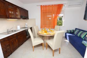 eine Küche mit einem Tisch und Stühlen sowie einem blauen Sofa in der Unterkunft Apartments Marin in Trogir