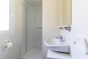 een witte badkamer met een wastafel en een douche bij Camping Daino in Pietramurata