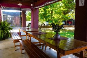 3 tables et bancs en bois sur un patio dans l'établissement Cabañas Parque Vistalba, à Luján de Cuyo