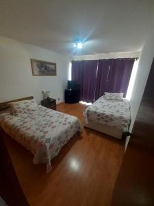 1 dormitorio con 2 camas y una ventana con cortinas moradas en Apartamento San Martin, en Viña del Mar