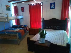 1 dormitorio con 2 camas y cortinas rojas en Hostel Paco House, en Monteverde