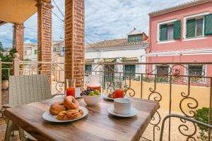 einen Holztisch mit Tellern aus Essen auf dem Balkon in der Unterkunft S&K Luxury Μaisonette in Potamós