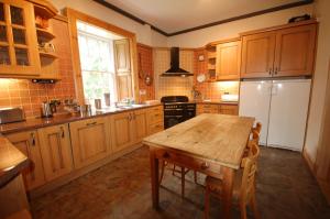 a kitchen with wooden cabinets and a wooden table at The Old Manse, Fochabers in Fochabers