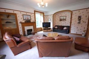 a living room with leather furniture and a fireplace at The Old Manse, Fochabers in Fochabers