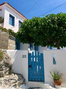 a blue door on a white building with a tree at Oikies Skiathos in Skiathos