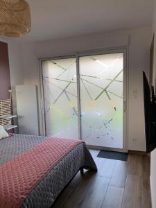 Schlafzimmer mit einem Bett und einer Glasschiebetür in der Unterkunft Les Chambres de Lily 1 in Lorgies