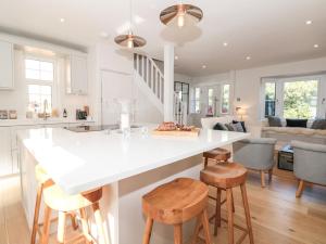 uma cozinha e sala de estar com um balcão branco e bancos em Marroy em Salcombe