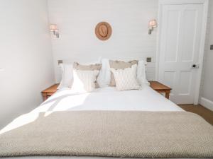 a white bed with pillows and a clock on the wall at Marroy in Salcombe